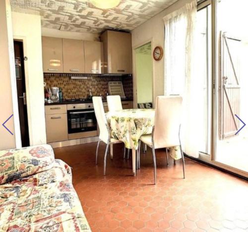 une cuisine avec une table et des chaises dans une pièce dans l'établissement Accès direct, plage, au Barcarès