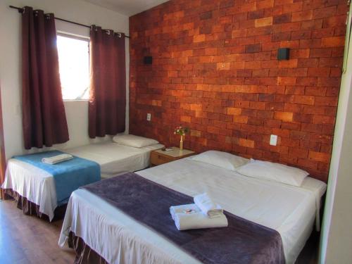 a hotel room with two beds and a brick wall at Pousada Sr. Ivan in Serra do Cipo