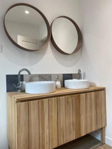 une salle de bain avec deux lavabos et deux miroirs dans l'établissement un petit coin sous les toits, à Hautvillers