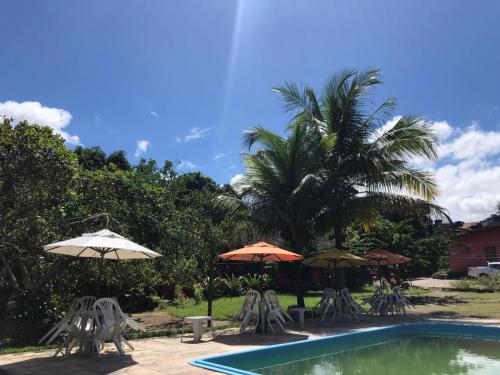 a swimming pool with chairs and umbrellas at Pousada Aba da Serra in São Joaquim do Monte