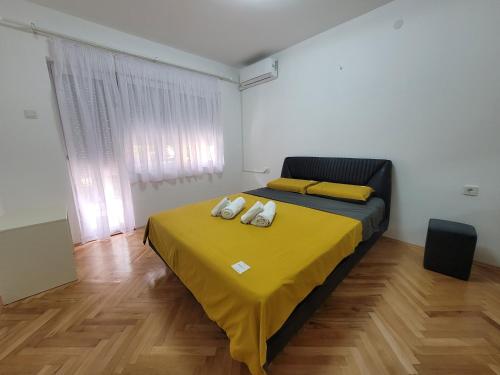 a bedroom with a bed with a yellow blanket on it at Happy apartment Strumica 2 in Strumica