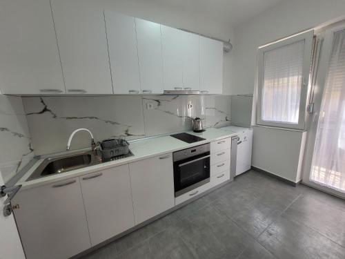 una cocina blanca con armarios blancos y fregadero en Happy apartment Strumica 2, en Strumica
