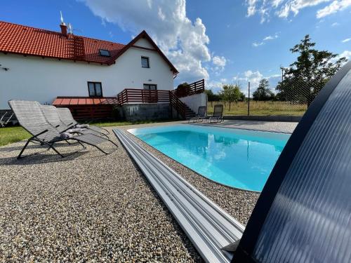 a swimming pool with a chair and a house at Chalupa Soběšice - kraj Šumavy in Soběšice