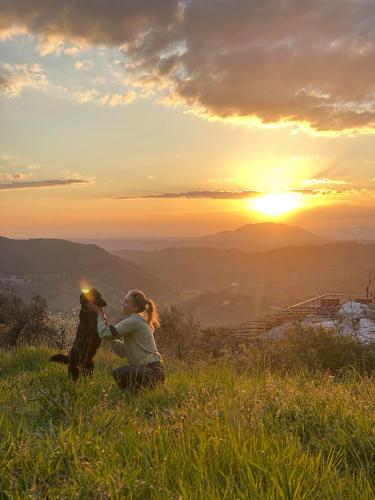 two people sitting on top of a hill at sunset at Agriturismo La Terrazza su Farfa in Castelnuovo di Farfa