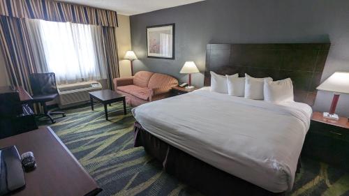 a hotel room with a large bed and a chair at Best Western Plus Philadelphia Bensalem Hotel in Bensalem