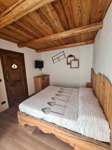 a bed in a room with a wooden ceiling at La Maison. La Roccia dello Stambecco in Bardonecchia