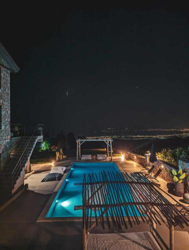 a swimming pool on the roof of a house at night at Three Dots Boutique Suites in Soúlion