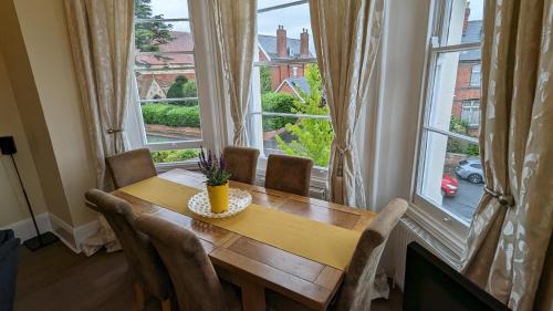 a dining room with a table and a large window at Upstairs Downstairs Regency Apartments in Cheltenham