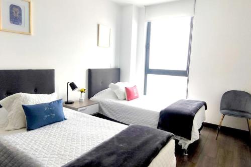 a bedroom with two beds and a chair and a window at Velasco MaiaHome-POLANCO Depa con alberca/gym/spa/jacuzzi + 3BR in Mexico City