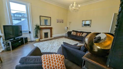 a living room with a couch and a tv at Upstairs Downstairs Regency Apartments in Cheltenham
