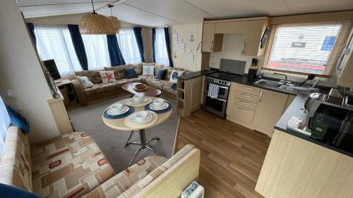 Cozy Private Static Caravan at Llyons Robin Hood - Silver Birch Way 11 في ريل: مطبخ وغرفة معيشة مع طاولة صغيرة في غرفة