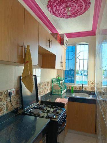 a kitchen with a stove top oven next to a sink at ROYAL APARTMENT MAKUPA in Mombasa