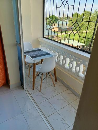 einen Tisch und einen Stuhl in einem Zimmer mit Fenster in der Unterkunft ROYAL APARTMENT MAKUPA in Mombasa
