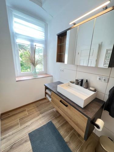 een badkamer met een witte wastafel en een raam bij Ferienwohnung Villa Einetal in Aschersleben