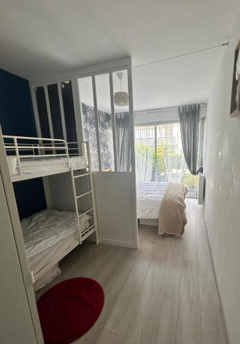 une chambre avec deux lits superposés et une fenêtre dans l'établissement Appartement terrasse privée grande plage à 100 m - Parking gratuit, à Saint-Cast-le-Guildo