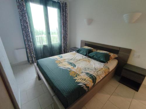 Ce lit se trouve dans une chambre dotée d'une fenêtre et d'un lit avec un couvre-lit. dans l'établissement Maison au calme vue montagnes, à Vence