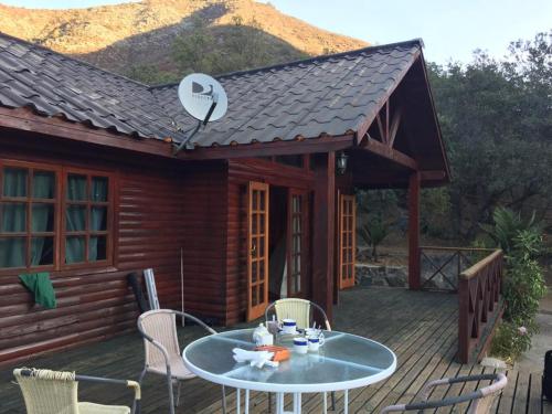 a house with a table and chairs on a deck at Cabañas Ocoa in Hijuelas