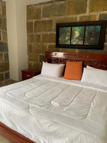 a large white bed with two orange pillows on it at Hotel Hacienda Guane Urbano in Oiba