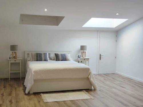 a white bedroom with a bed and a skylight at Mazi Apartments Cuba in Mataró