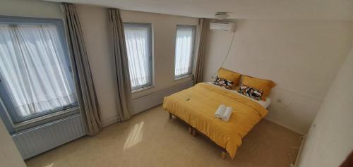 a bedroom with a yellow bed and two windows at Sunset de Luz in Nijmegen