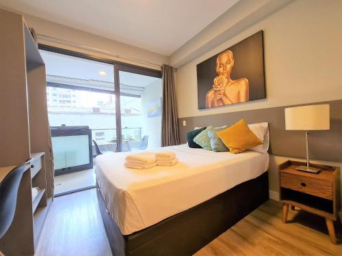 a bedroom with a large bed with a large window at Studio Benê em Pinheiros. in Sao Paulo