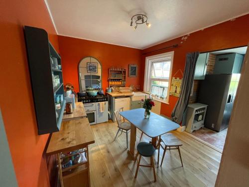 a kitchen with orange walls and a table and chairs at Maisonette - Halfway down to Swanage or up to Durlston in Swanage