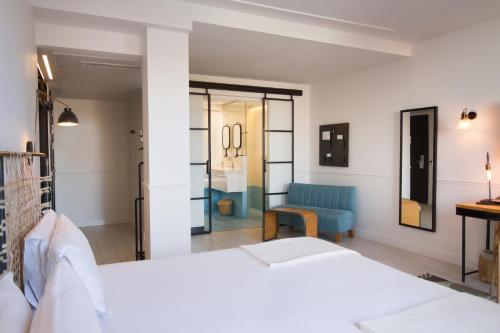 a bedroom with a white bed and a blue chair at 7 Islas Hotel in Madrid