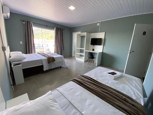 a bedroom with two beds and a large window at Pousada da Bia Praia in Penha