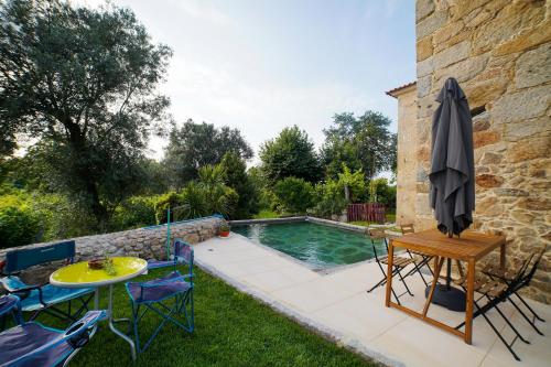 eine Terrasse mit Tisch und Stühlen neben einem Swimmingpool in der Unterkunft Casa do Ribeiro in Lago