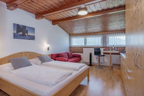 1 dormitorio con 1 cama grande y 1 sofá rojo en Haus Scheiblauer, en Tröpolach