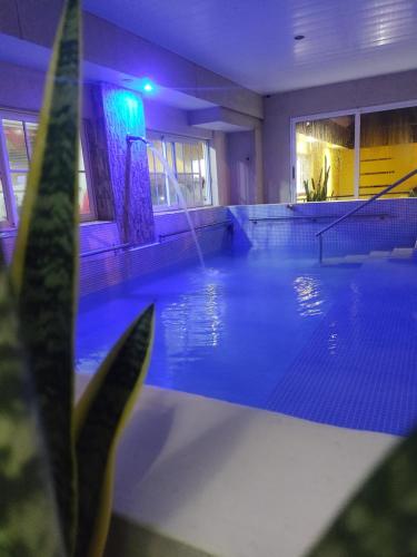a swimming pool with blue lighting in a building at Apart Termal Centro in Termas de Río Hondo