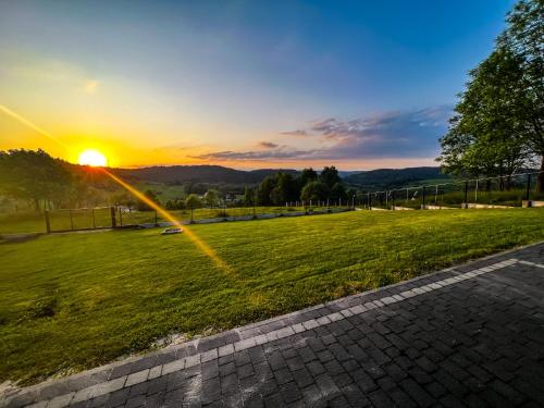 a sunset over a field with the sun setting at Beskidzki Domek Kurów in Kurów