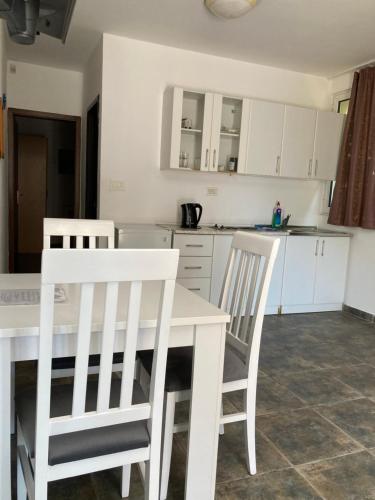 a kitchen with white chairs and a white table at Mijovic Apartments in Budva