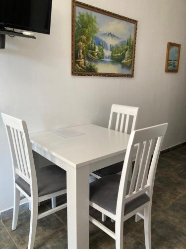 a white table with four chairs and a painting on the wall at Mijovic Apartments in Budva