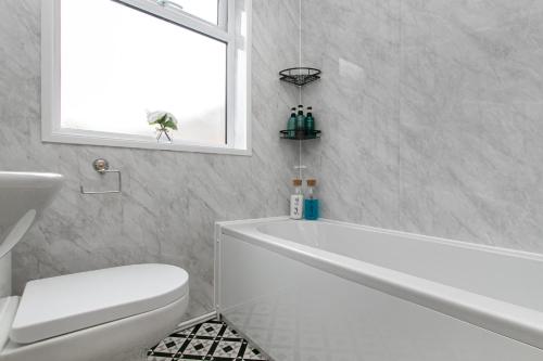 Un baño con bañera, inodoro y ventana. en Mill Dam Lake House, en Saint Osyth