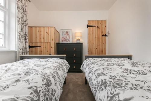 1 dormitorio con 2 camas y armarios de madera en Mill Dam Lake House, en Saint Osyth