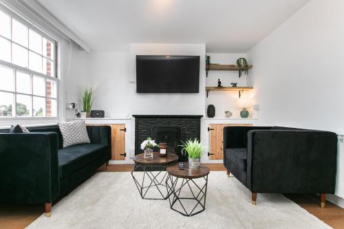 a living room with two black couches and a fireplace at Mill Dam Lake House in Saint Osyth