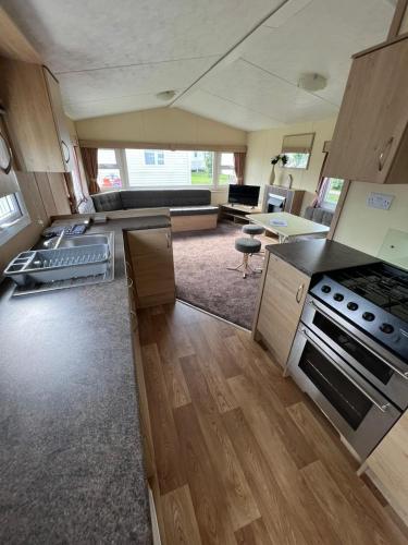 a large kitchen with a stove and a living room at Golden Palm Resort, Sherwood Plot, Jubilee S216, 8 Berth in Chapel Saint Leonards