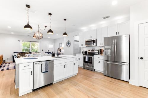 una cocina con armarios blancos y electrodomésticos de acero inoxidable en Serenity Pearl Escape, en St. Augustine
