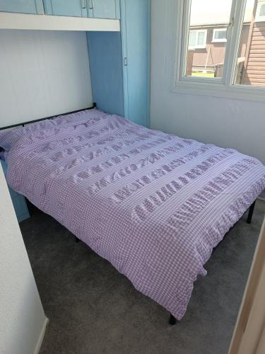 a purple bed in a room with a window at Chalet 281 Golden Sands Holiday Park in Withernsea