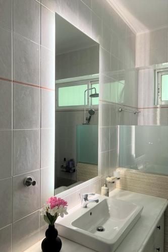 a white bathroom with a sink and a mirror at Sea, La Vie in Saronida