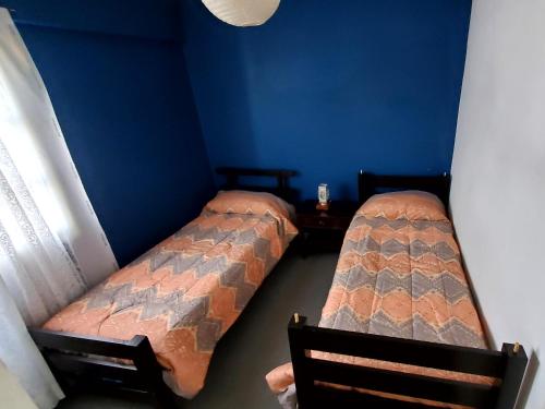 2 camas individuales en una habitación con una pared azul en Lo de Vega en San Salvador de Jujuy