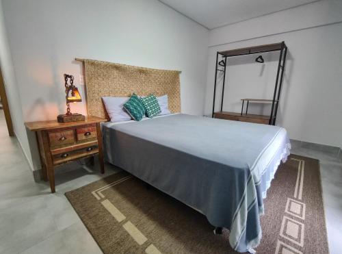 a bedroom with a bed and a dresser and a mirror at Apto Astúrias Guarujá in Guarujá