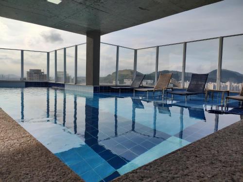 a swimming pool on the top of a building with windows at Apto Astúrias Guarujá in Guarujá