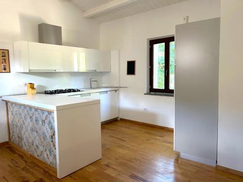 a kitchen with white cabinets and a wooden floor at L'Araucaria Suite Il Ginepro in Riola Sardo