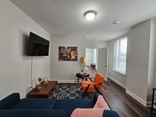 a living room with a blue couch and an orange chair at Luxurious 1 Bed 1 Bath Stay at the Historic Inman in Champaign