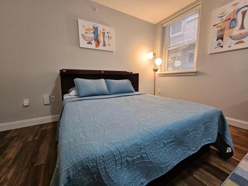 a bedroom with a bed with blue sheets and a window at Cozy Studio at the Historic Inman in Champaign