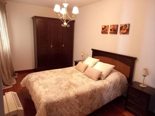 Un dormitorio con una cama grande y una lámpara de araña. en Apartamento Ribeira, en Ribeira