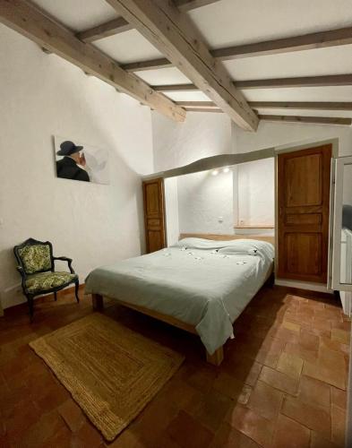une chambre avec un grand lit et une chaise dans l'établissement Maison Pipette Pipette Maison, au Castellet