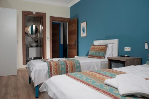 a bedroom with two beds and a blue wall at Mavi Yaprak Hotel in Oludeniz